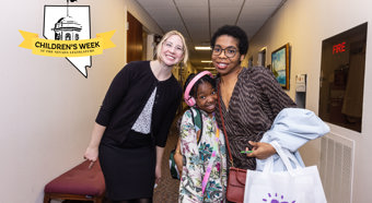 To young women stand with young girl in hallway, all smiling at camera 