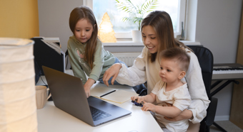 Little boy and little girl sitting with women in an at home office setting. Everyone is smiling 