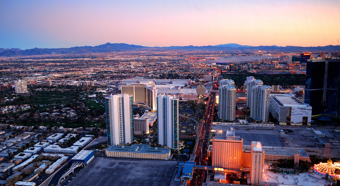 Aerial shot of downtown Las Vegas during sunset, mountains in back, city in front 