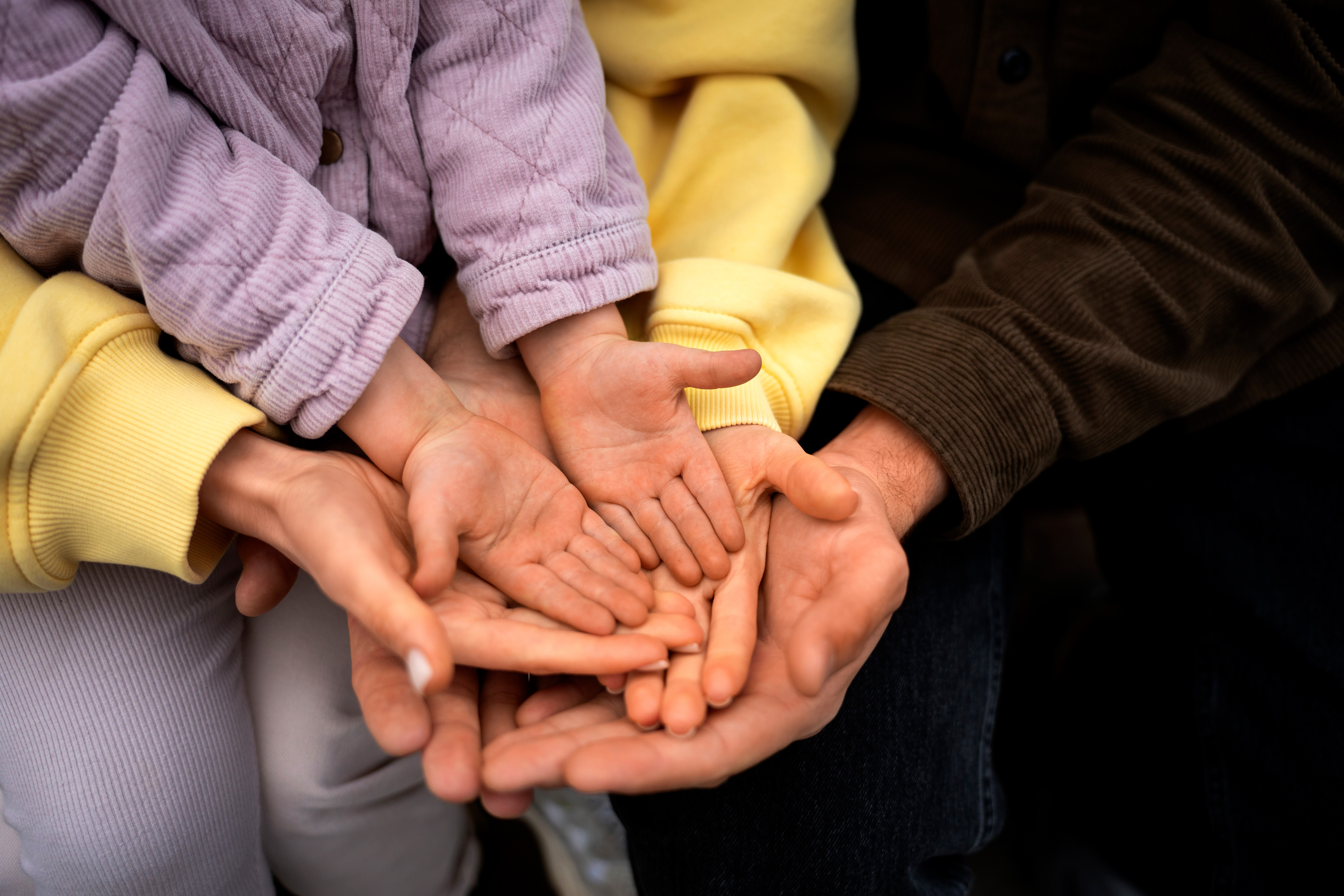 Two parental figures hands holding a toddlers hand