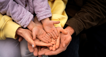 Two parental figures hands holding a toddlers hand