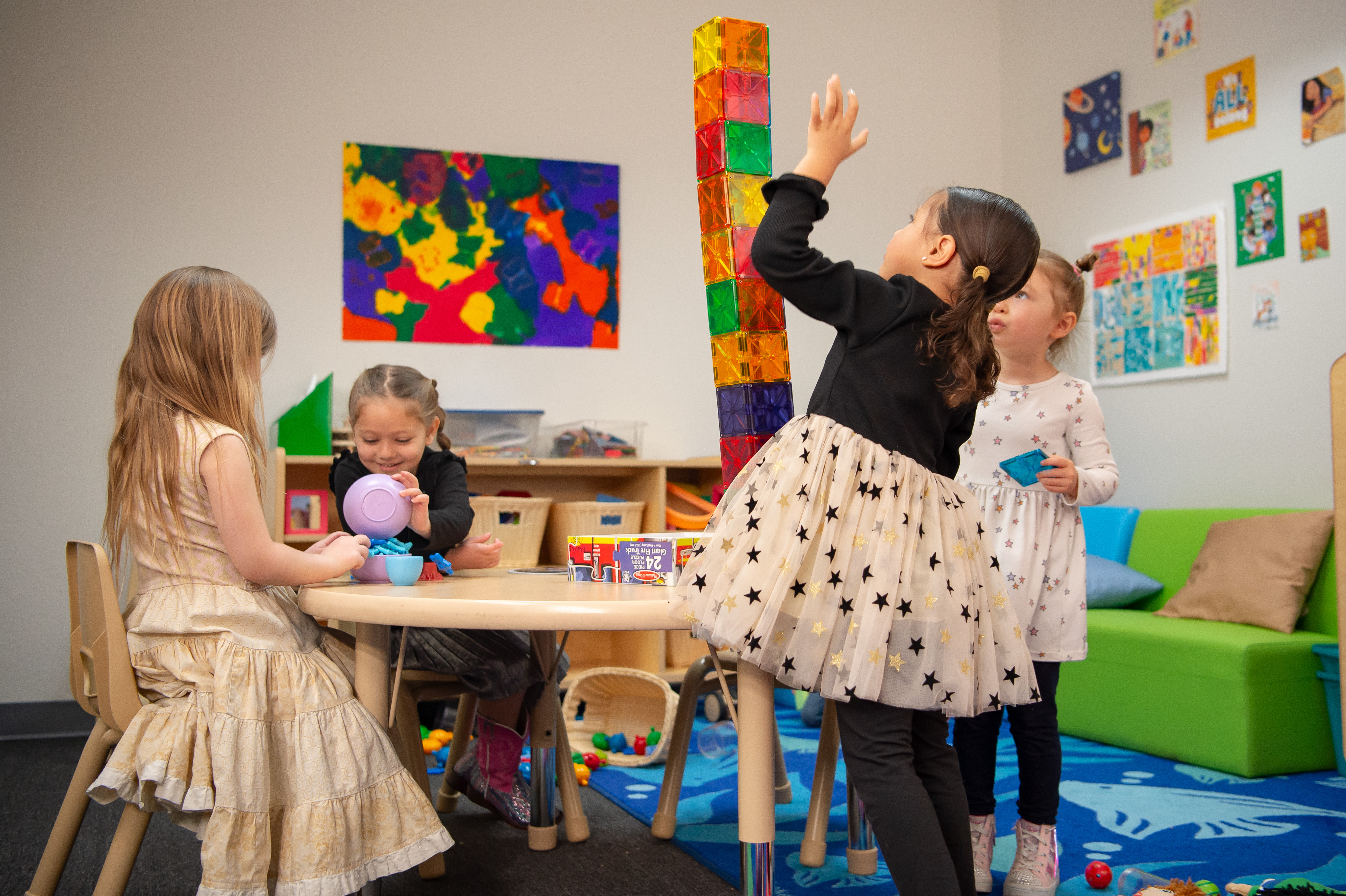 Four little girls in colorful classroom setting playing with toys