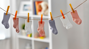 7 colored toddler sized socks hanging on a clothes line indoors.