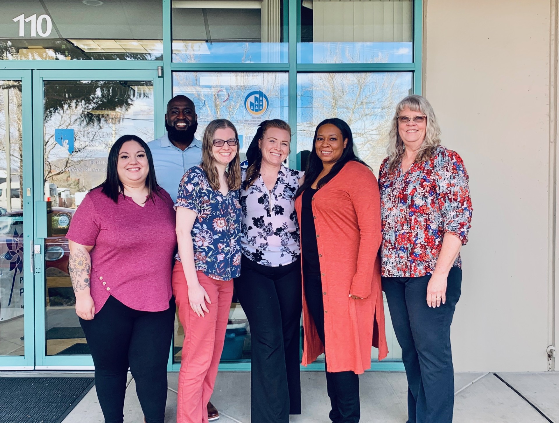 The Child Care Excellence Academy staff standing outside a building posing and smiling for the photo.
