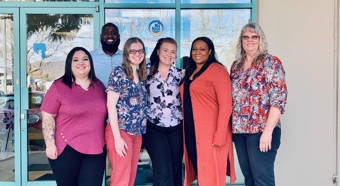 The Child Care Excellence Academy staff standing outside a building posing and smiling for the photo.
