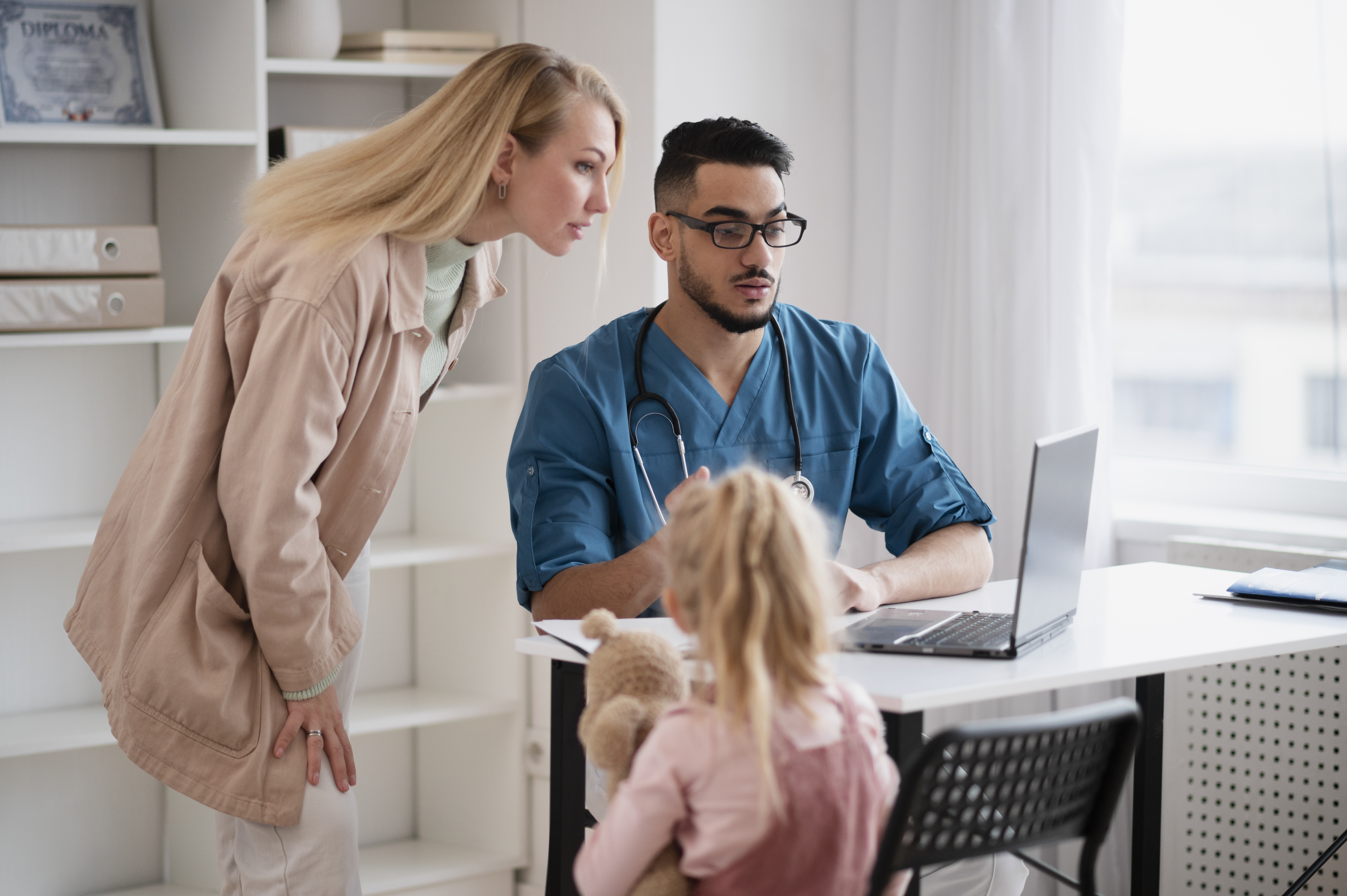 Blonde women and blonde girl talking to a medical professional in their home