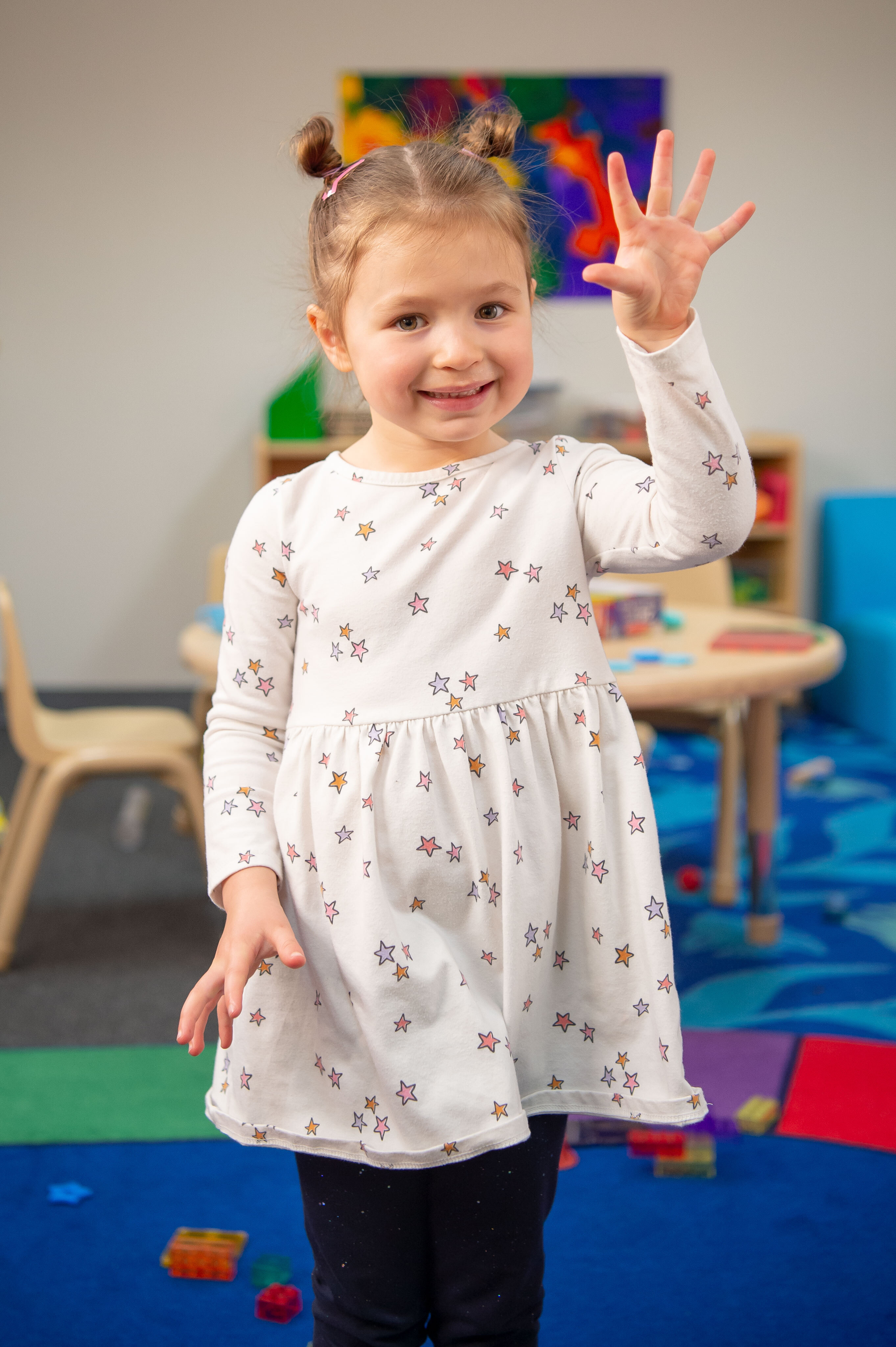 Young girl with light skin and hair in pig tails holding up 5 fingers.