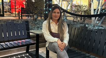 Alejandra Melecio looking at camera sitting on bench in an outdoor setting