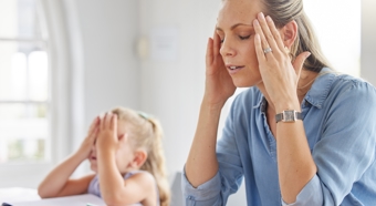 Blonde haired women and young girl sitting at table with their hands on the heads, showing frustration