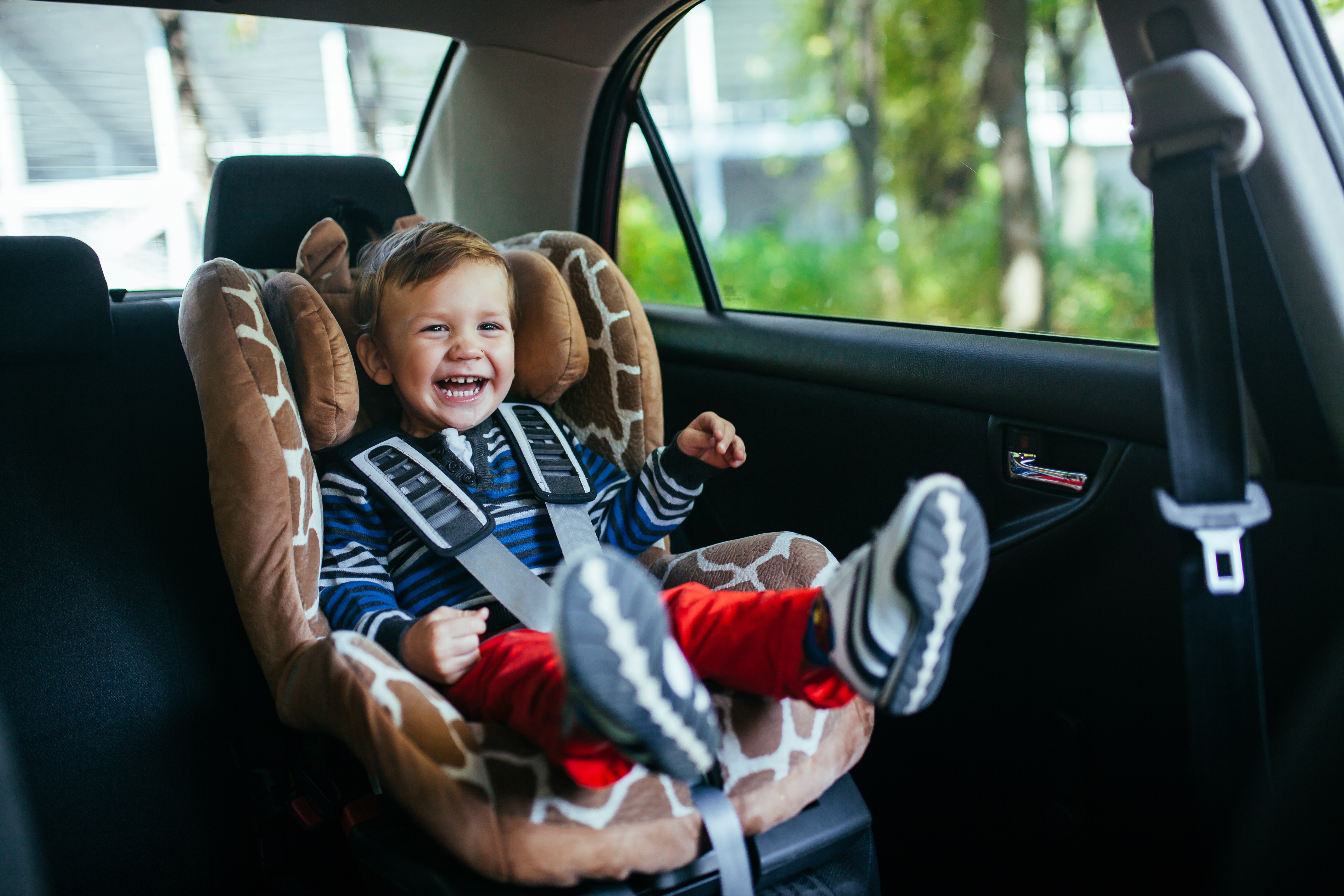 Adorable, smiling baby boy sitting in a Safety Car Seat