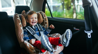 Adorable, smiling baby boy sitting in a Safety Car Seat