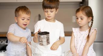 Three young kids in a home kitchen helping with some basic cooking.