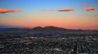 Aerial shot of Nevada skyline during sunset, mountains in background and city buildings in front 