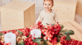 Cute litte girl smiles while standing in a room with holiday decorations around her