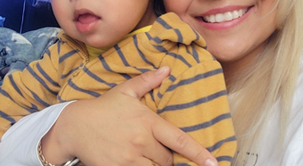 Ana Elizabeth Saucedo Gutierrez holding baby and smiling at camera 
