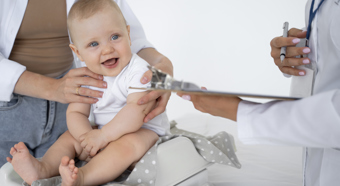 Baby at doctors office with big smile on his face.